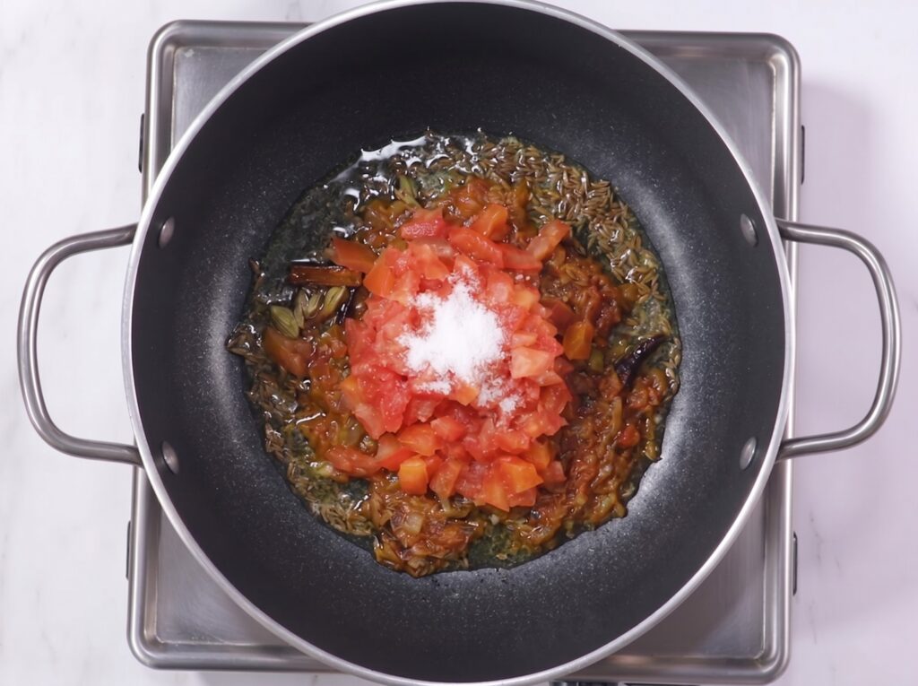 Homemade palak paneer recipe showing tomato onion masala cooking in a pan